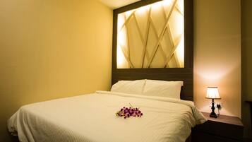 A hotel room with a bed, a nightstand with a lamp, and a decorative wall panel.