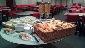 A buffet setup with various food items and a basket of baguettes.