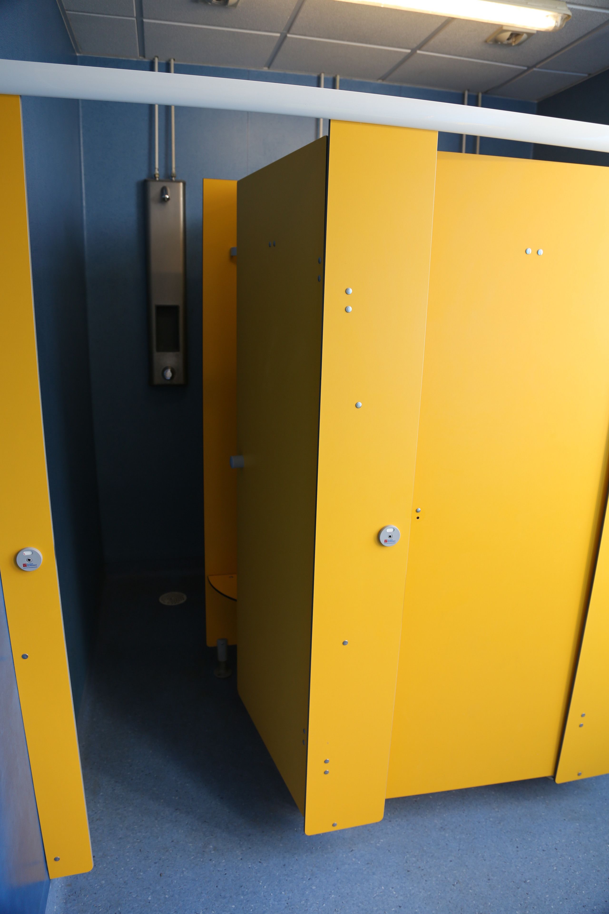 A restroom with yellow partitions and a visible electrical panel on the wall.