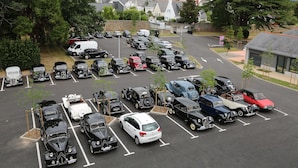 A parking lot with various vintage cars and a few modern vehicles.