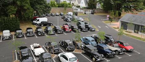 A parking lot with various vintage cars and a few modern vehicles.