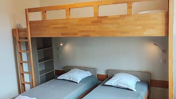 Una camera del dormitorio con due letti singoli, una cuccetta in legno, una scrivania e una sedia.