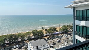 Vista di una spiaggia da un edificio con un balcone, un parcheggio e cielo sereno.
