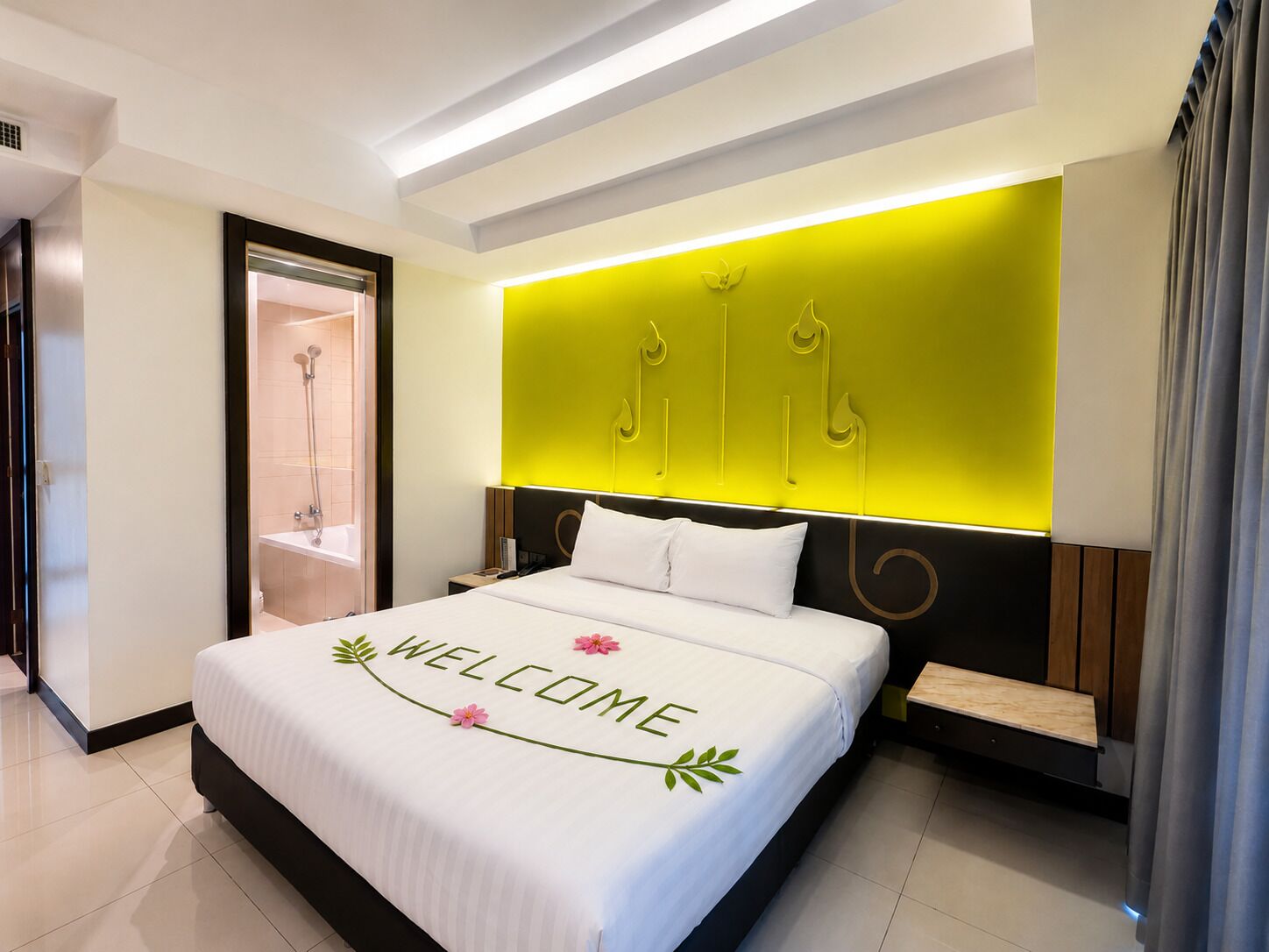 A modern hotel room with a bed, a bedside table, a nightstand, a built-in shower, and a bright accent wall.