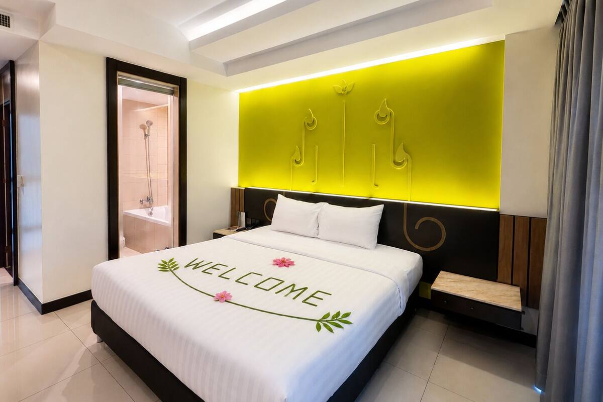 A modern hotel room with a bed, a bedside table, a nightstand, a built-in shower, and a bright accent wall.