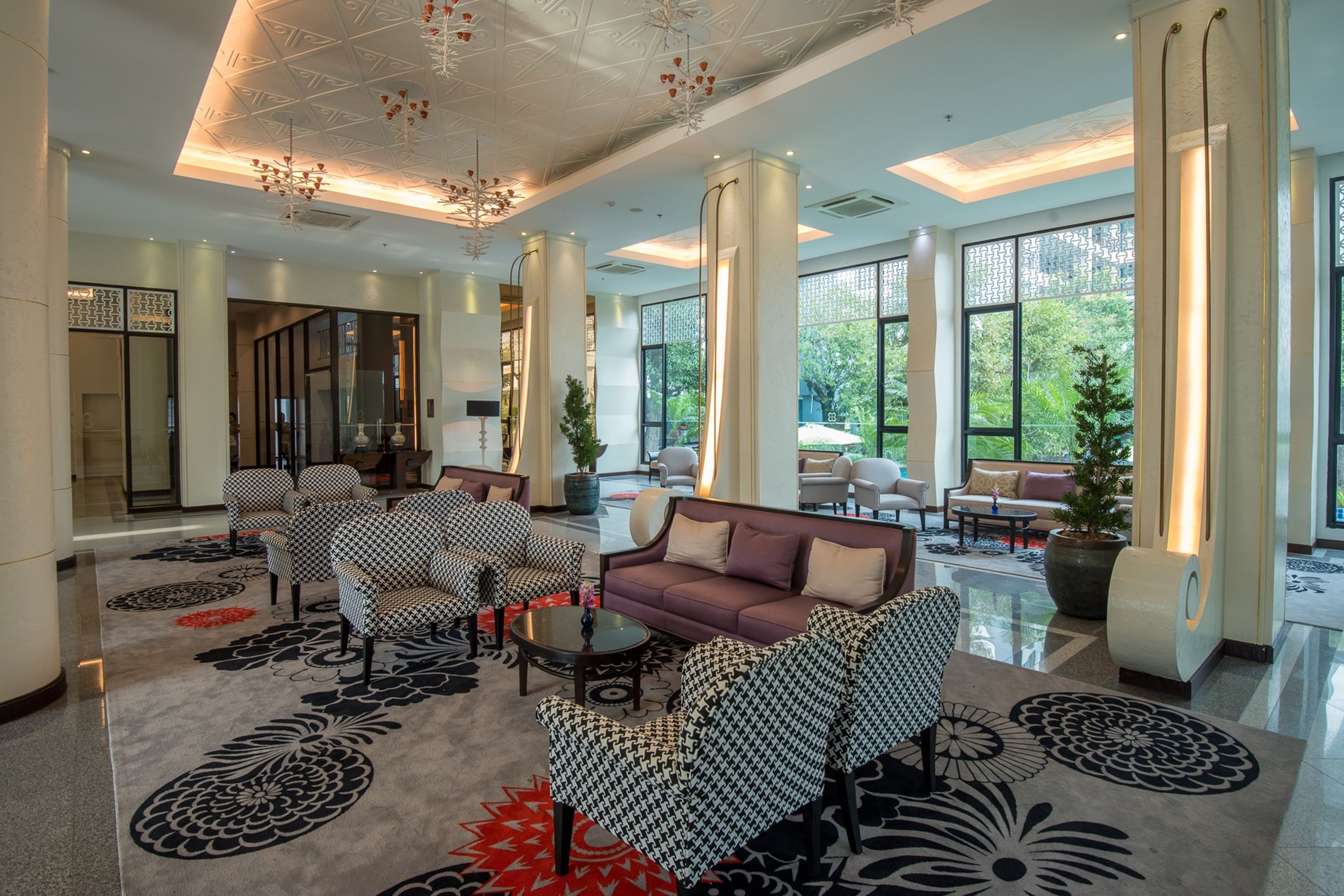 A spacious lobby with a modern chandelier, patterned carpet, and a seating area with sofas and chairs.