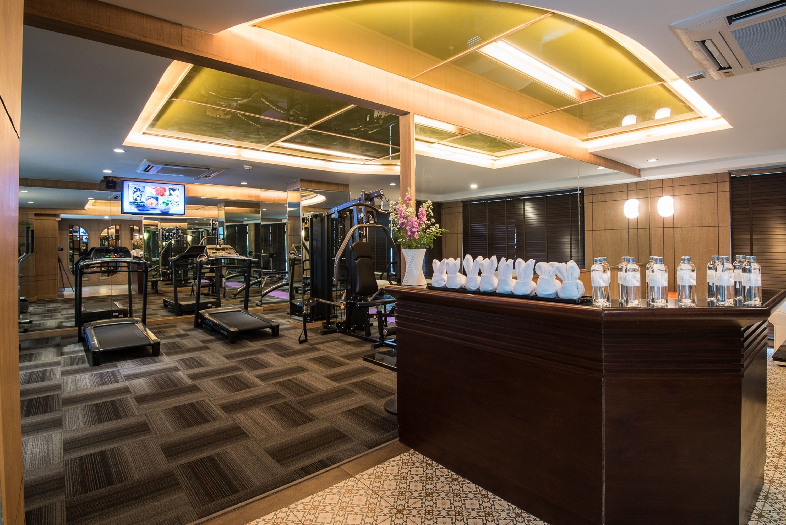 A gym with treadmills, exercise machines, and a reception desk with water dispensers.