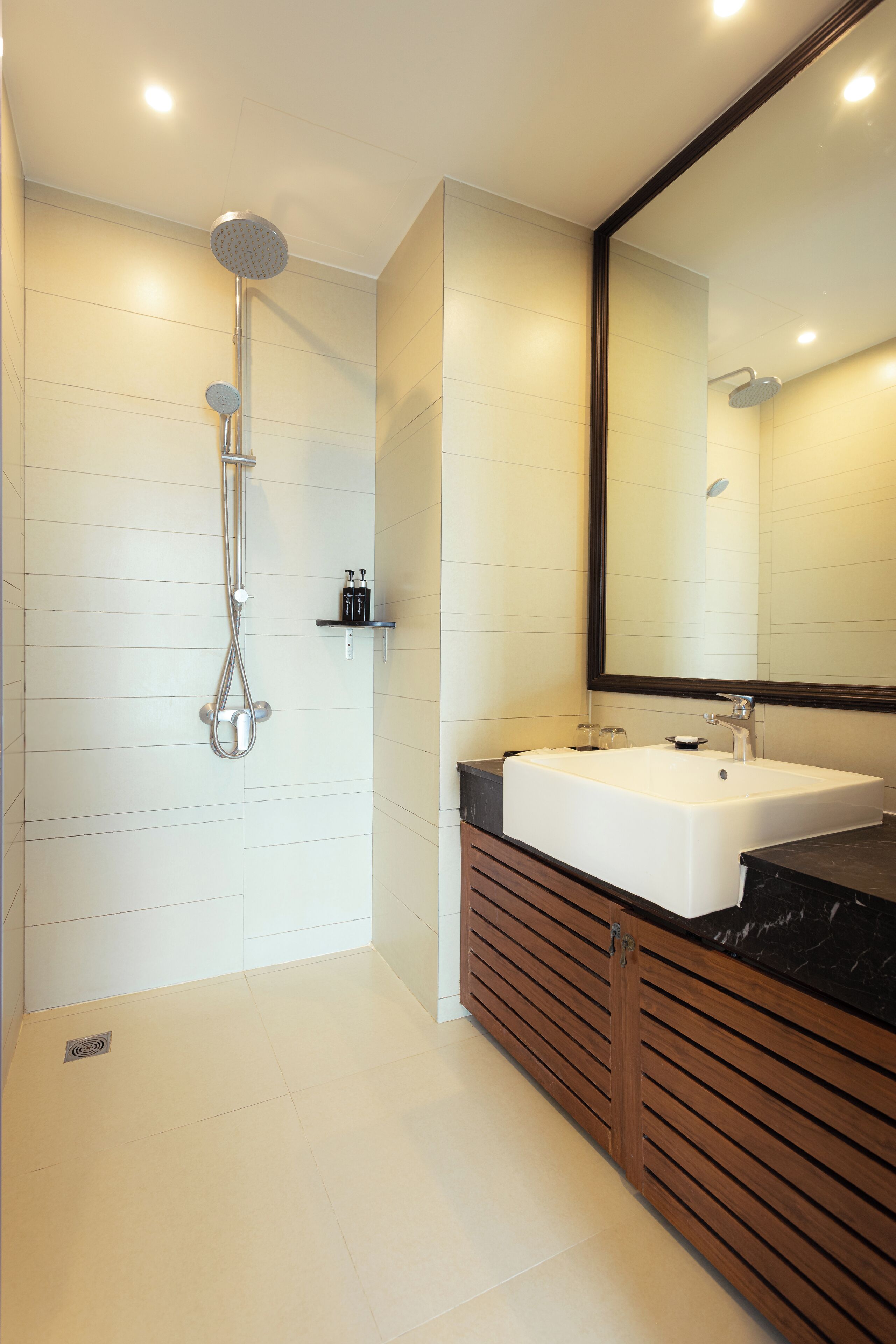 A modern bathroom with a large mirror, a white sink, and a shower head.