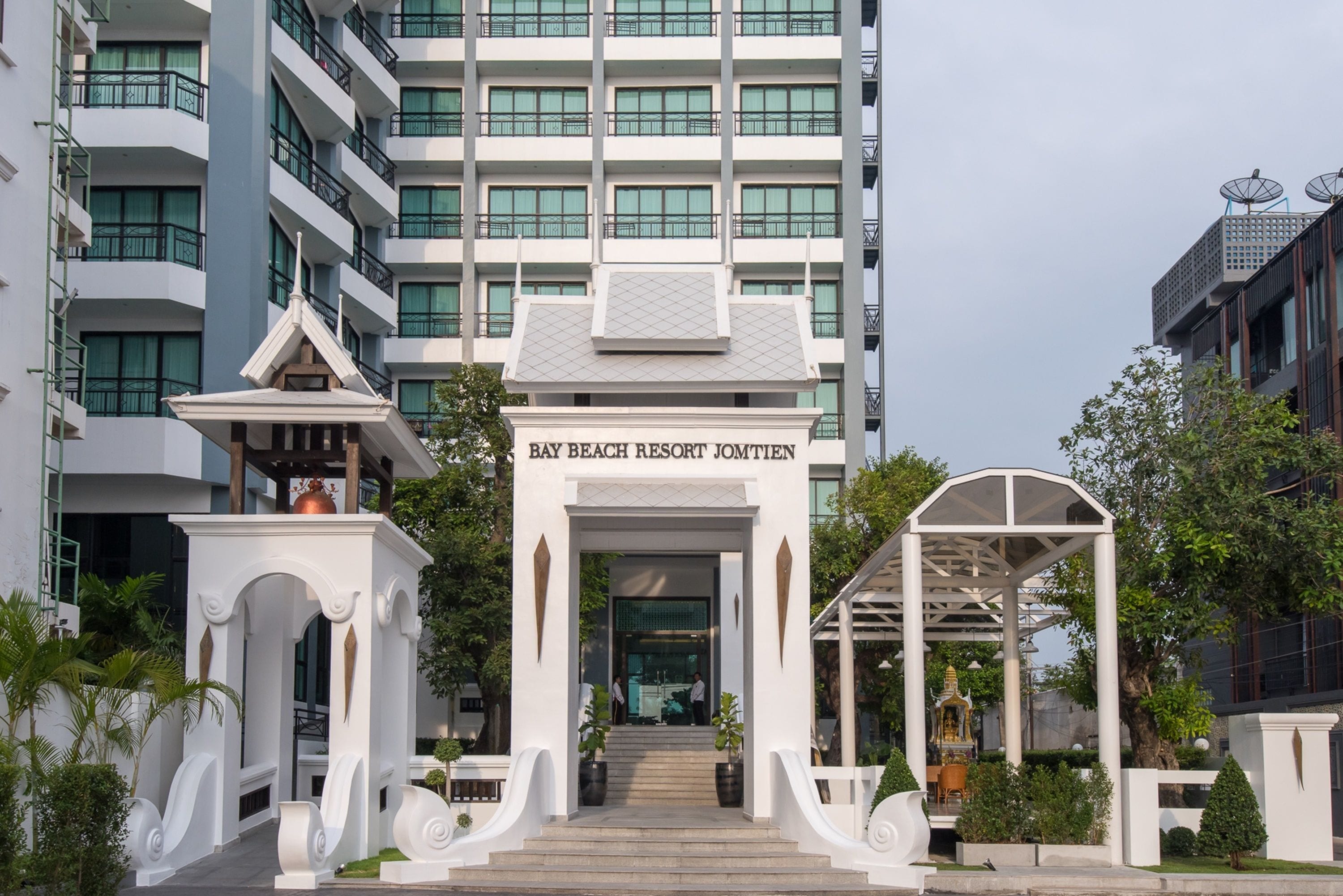 A hotel entrance with a sign reading "Bay Beach Resort Jomtien".