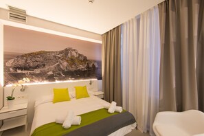Une chambre d’hôtel avec un lit, une table de chevet, une lampe et une vue sur une côte rocheuse.