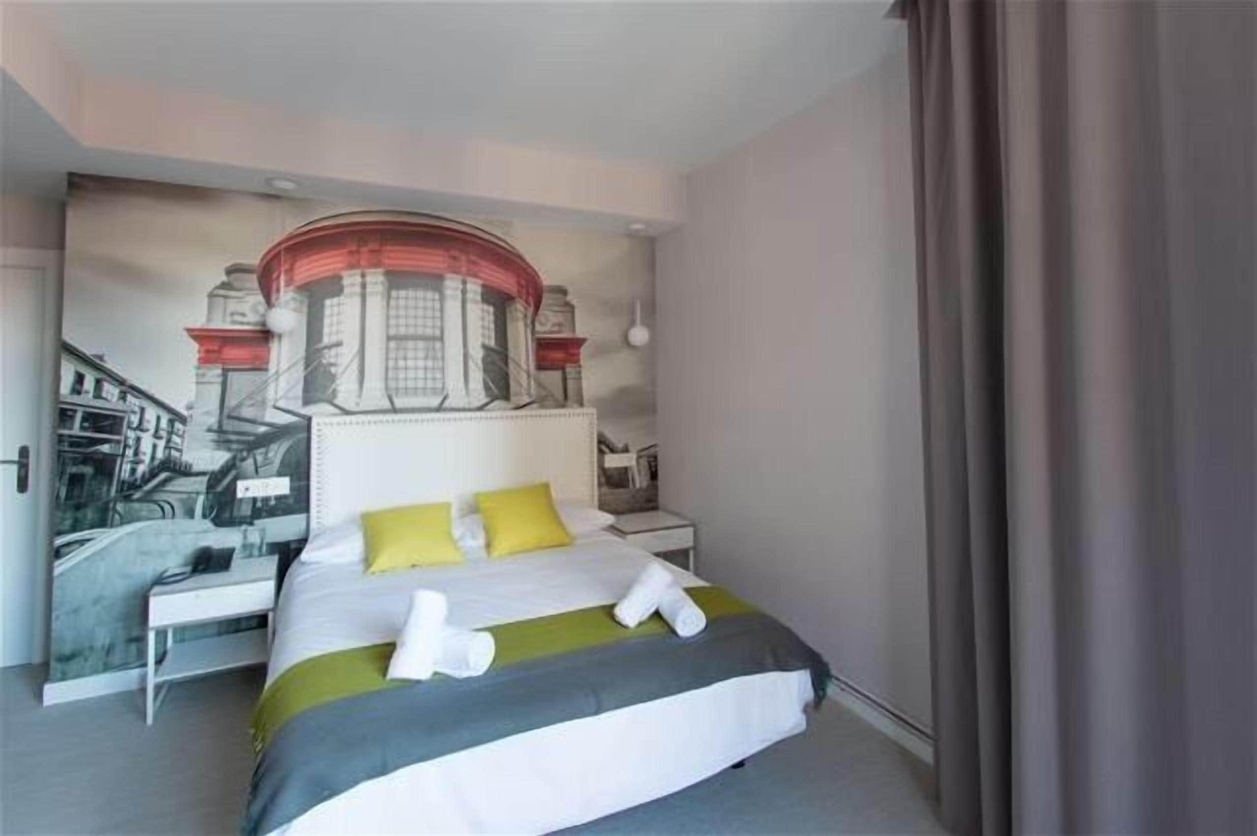 Una habitación de hotel con cama, escritorio y un gran mural en la pared.