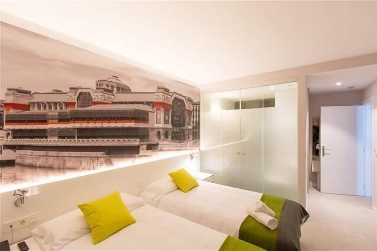 A hotel room with two beds, a large window, a mural of a train, and a walk-in closet.