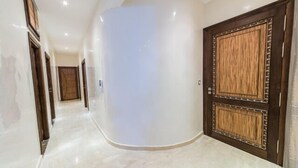 A hallway with a curved wall, a wooden door with a decorative frame, and a wooden door at the end. - Apartment 3 Rooms city center Fes (Fes)