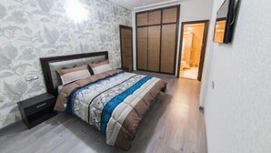 A bedroom with a bed, nightstand, wardrobe, and a door leading to another room. - Apartment 3 Rooms city center Fes (Fes)