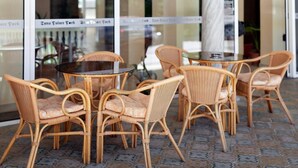 Des chaises en osier et une table ronde devant un bâtiment dont les portes sont en verre.