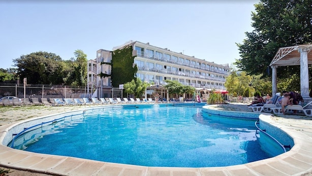 Une piscine avec des chaises longues et un bâtiment en arrière-plan.