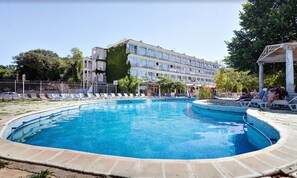 A swimming pool with lounge chairs and a building in the background. - Dana Palace (Golden Sands)