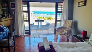 Una habitación con cama, silla, mesa y vista al océano.