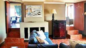 Una sala de estar con chimenea, un sofá, una lámpara y un cuadro de veleros.