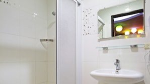 Un baño con cabina de ducha de vidrio, un lavamanos blanco y un espejo sobre el lavamanos.