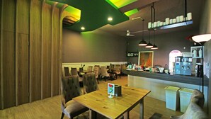 Un restaurante con muebles de madera, una barra y un techo con detalles de iluminación verde.