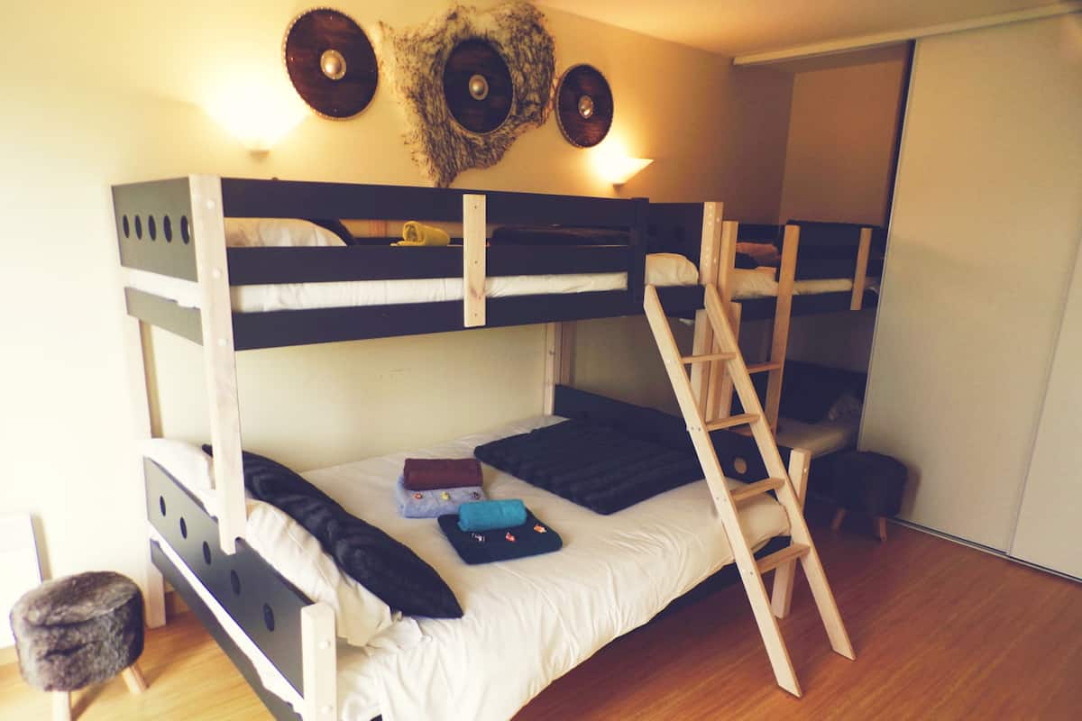 Una cama litera con escalera, un taburete pequeño y un adorno en la pared.