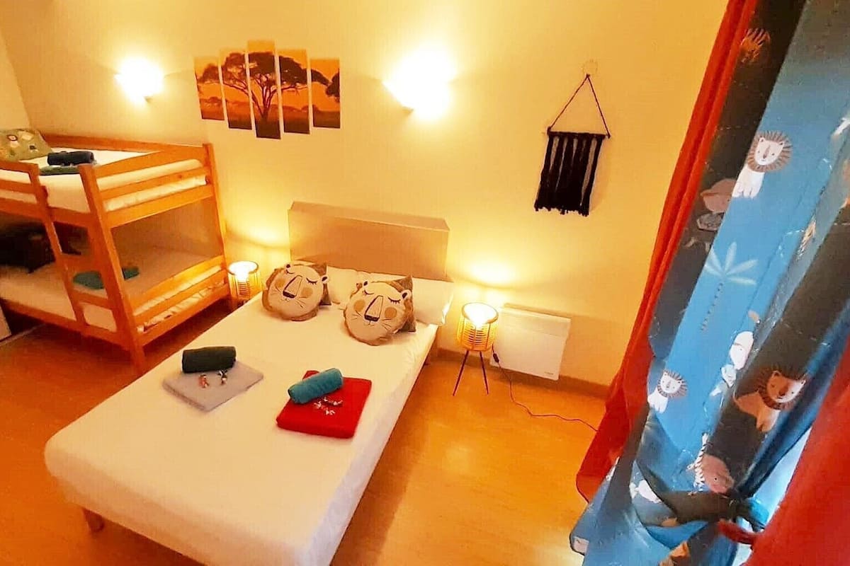 Una habitación con una cama nido, una mesita de noche con lámpara, y una pared decorada con cuadros.