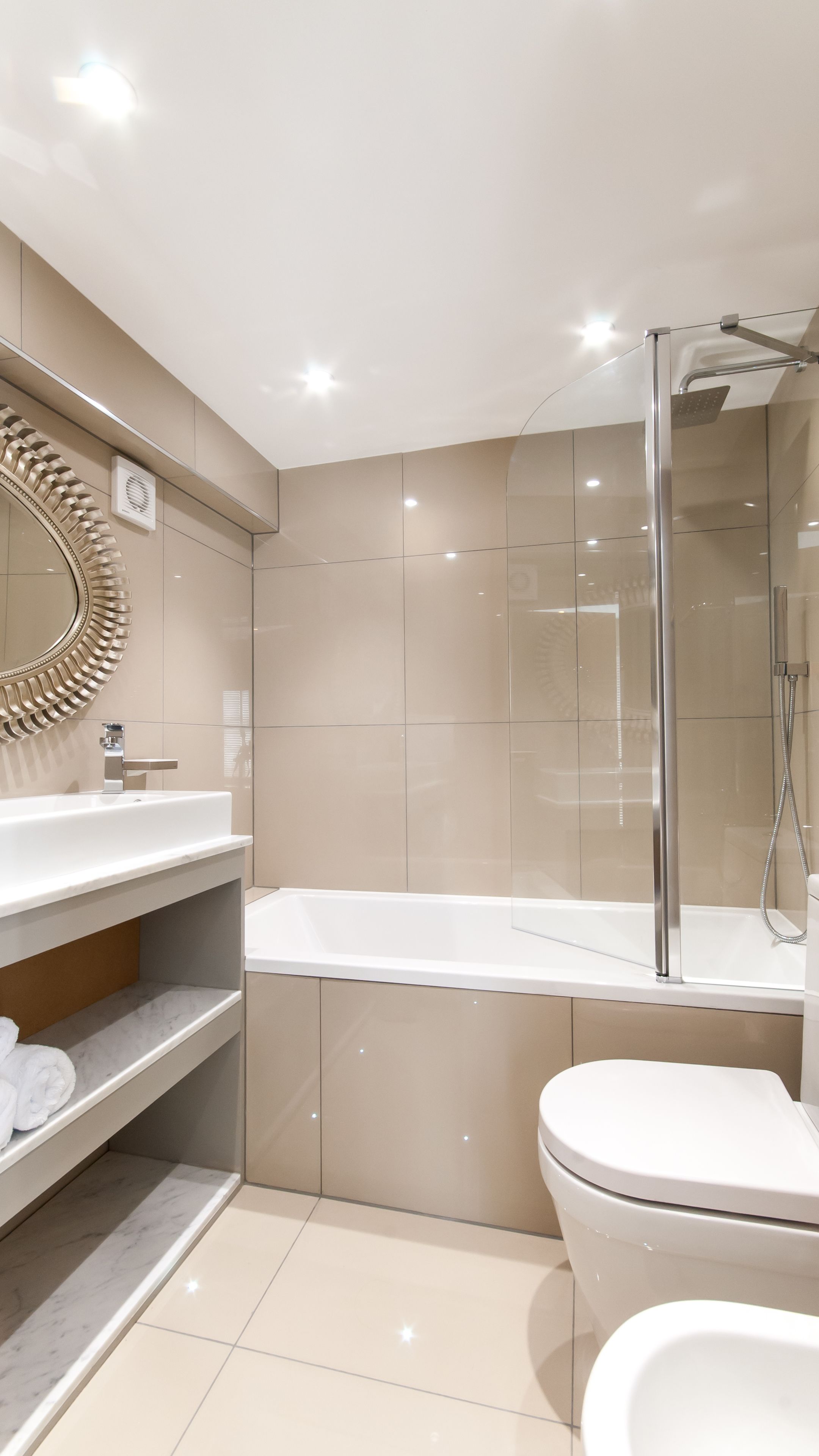 A modern bathroom with a glass-enclosed shower, a white sink, and a toilet.