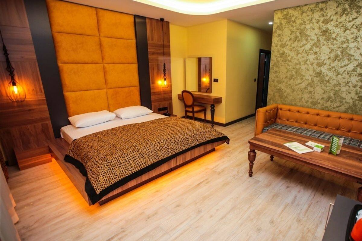 A hotel room with a bed, a sofa, a desk, and a mirror.