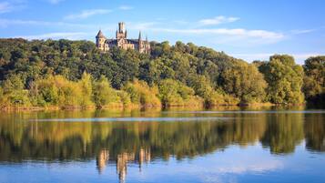 Um castelo numa colina, com um lago em primeiro plano.