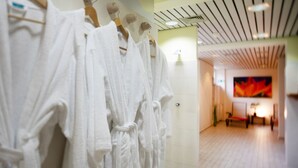 A hotel hallway with white robes hanging on a rack, a painting on the wall, and a wooden floor. - Leine Hotel (Pattensen)