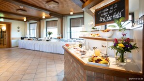 A hotel breakfast area with a buffet table, a sign indicating the hotel name, and a flower arrangement. - Leine Hotel (Pattensen)