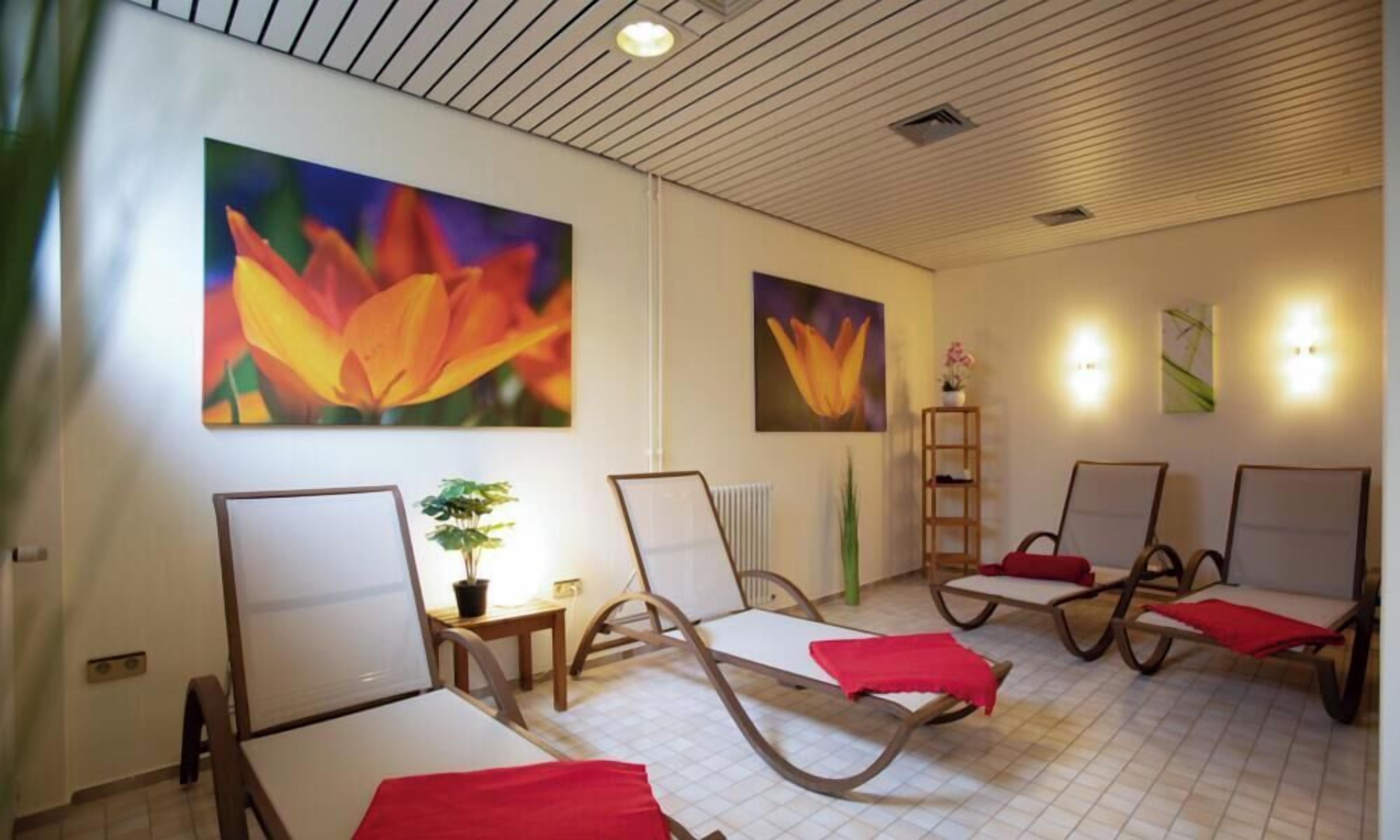 Une pièce comprenant quatre fauteuils inclinables, une petite table avec une plante et deux appliques murales.