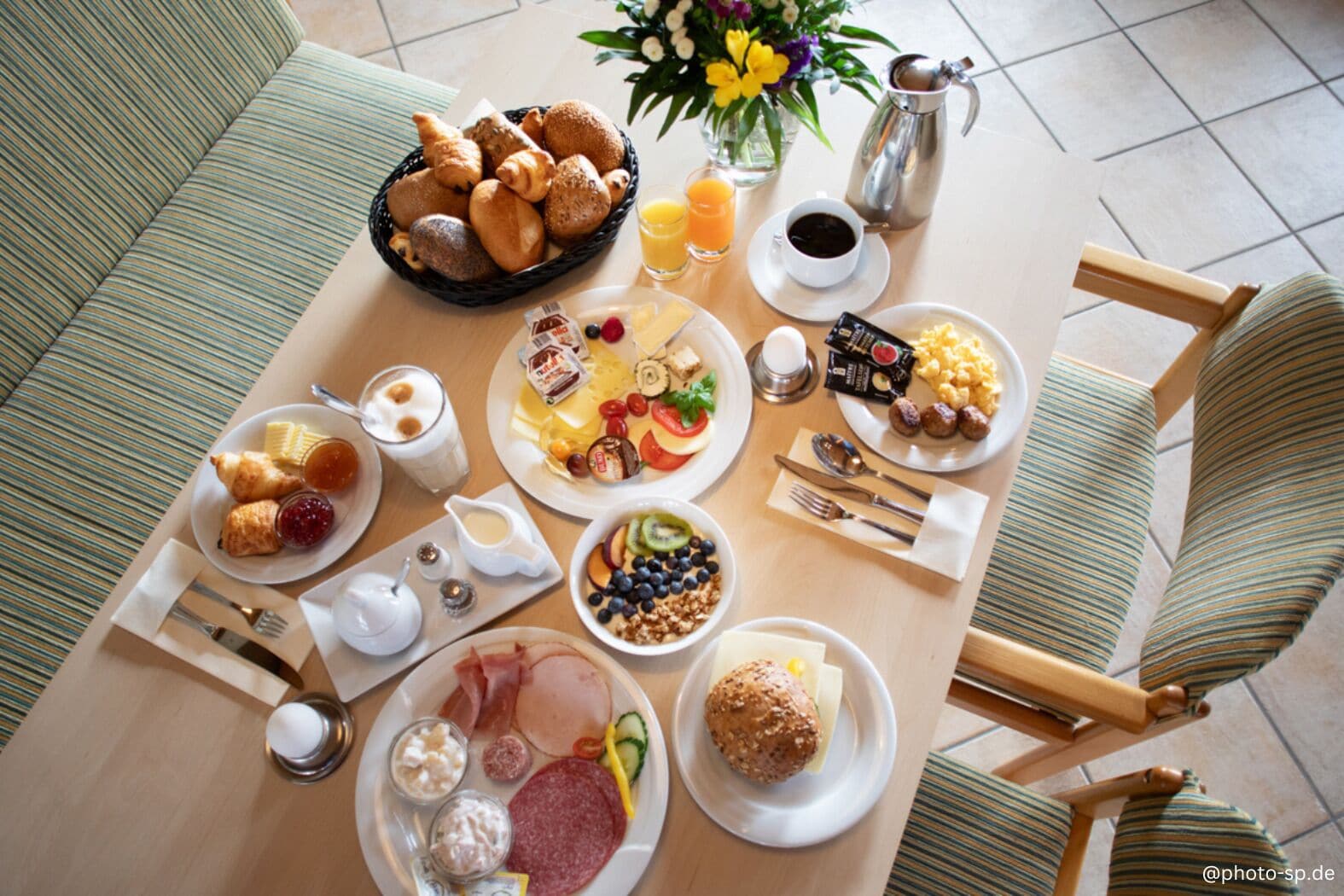 Un buffet de petit-déjeuner proposant divers aliments, une cafetière et un vase rempli de fleurs.