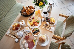 Un bufé de desayuno con diversas opciones de comida, una cafetera y un jarrón con flores.