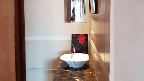 Un baño con un lavamanos blanco, un espejo y un cuadro en la pared.