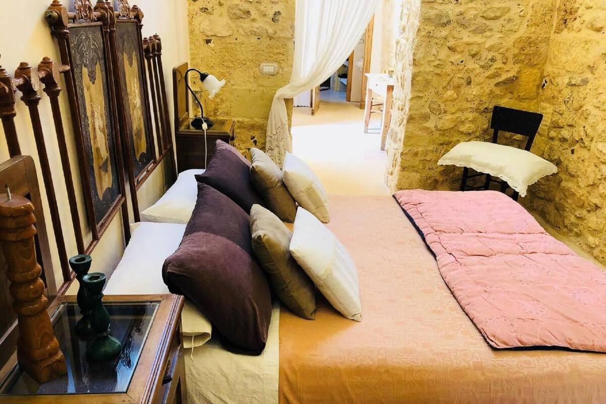 Une chambre à coucher avec un lit, une chaise, une table avec une lampe et un miroir.