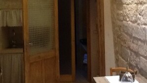 A room with a wooden door, a table with a glass dome, and a stone wall. - Borgoincorte (Martano)