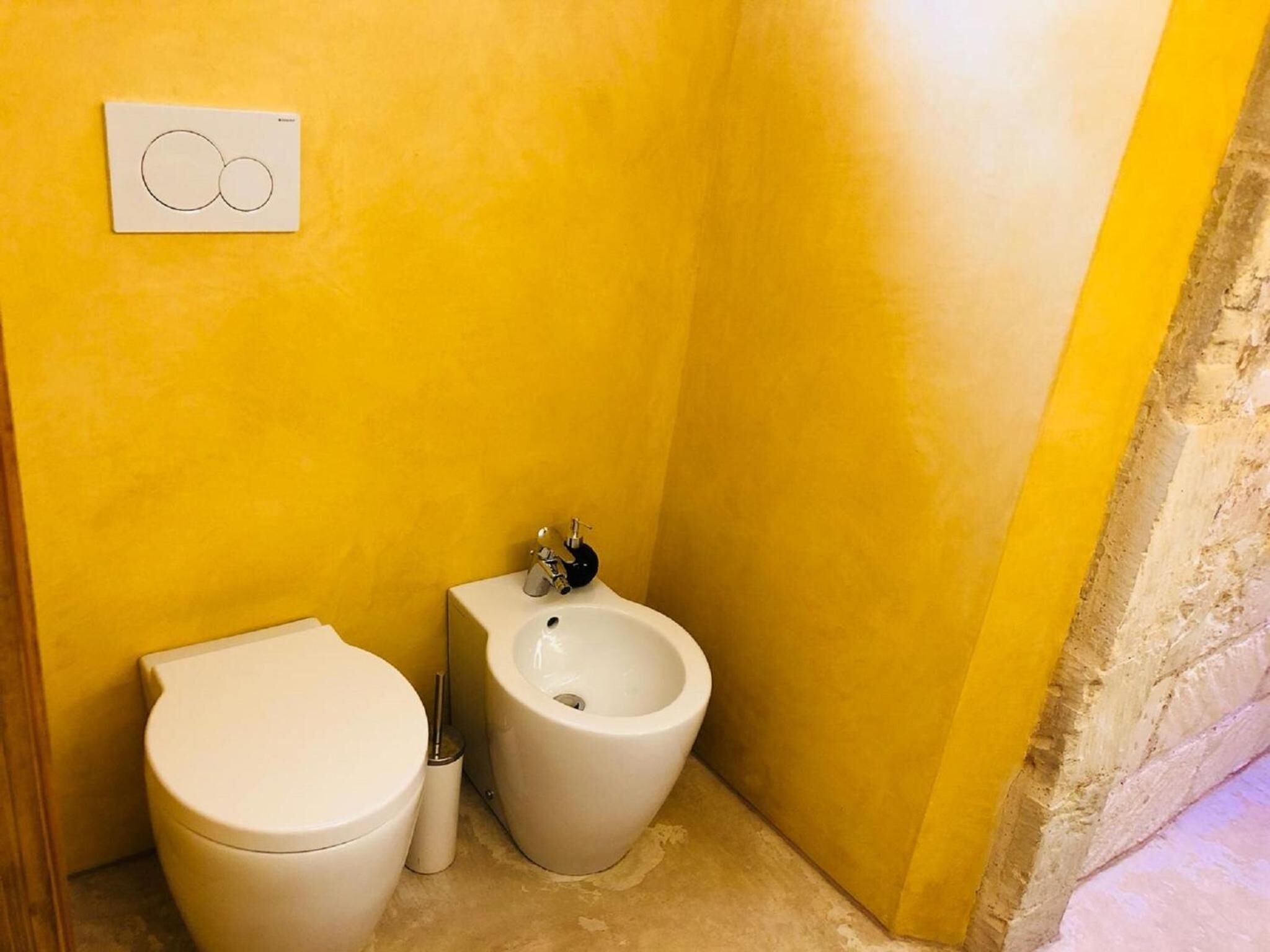 Un baño pequeño con inodoro, bidé e interruptor de luz en la pared.