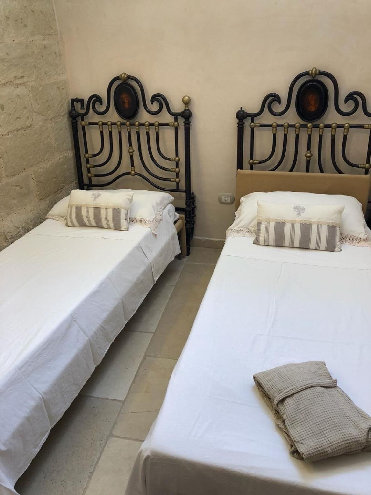 Dos camas individuales con cabeceros de madera, ropa de cama blanca y almohadas a rayas.