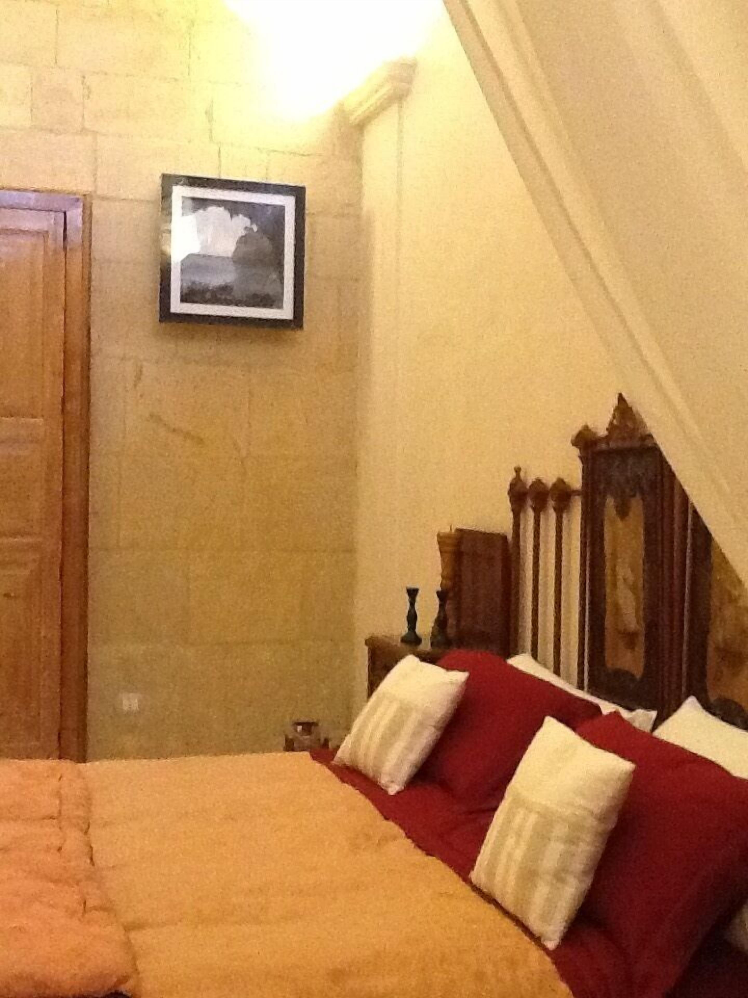 Une chambre à coucher avec un lit, une tête de lit en bois, une table de chevet et un tableau encadré au mur.
