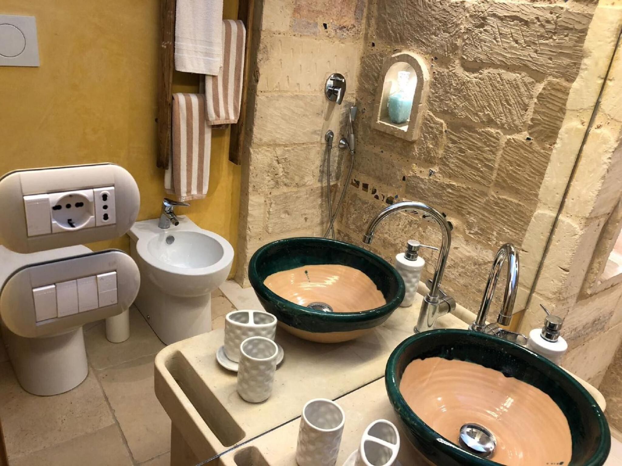 A bathroom with two bidets, a large green ceramic sink, and a white pedestal bidet.