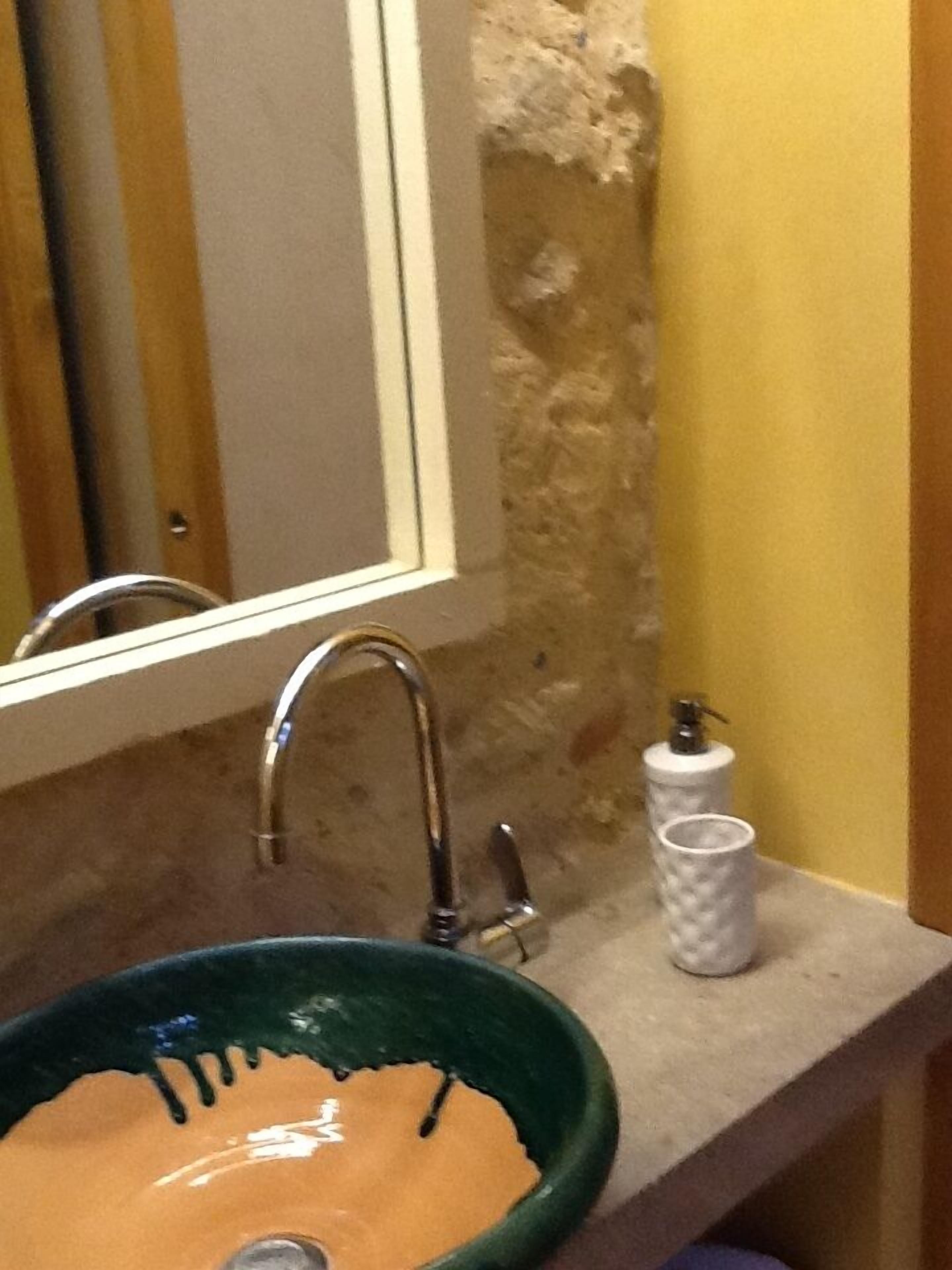 A bathroom with a green ceramic sink, a mirror, and a towel dispenser.