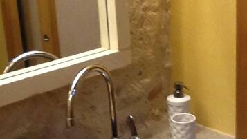 A bathroom with a green ceramic sink, a mirror, and a towel dispenser.