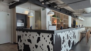 A modern reception desk with a cow print design, a sign reading 'IHG ONE REWARDS', and a bar area with stools. - Holiday Inn - the niu, Dairy Haarlem by IHG (Haarlem)
