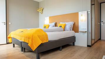 Quarto de hotel moderno com cama, mesa de cabeceira e luminária fixada na parede.