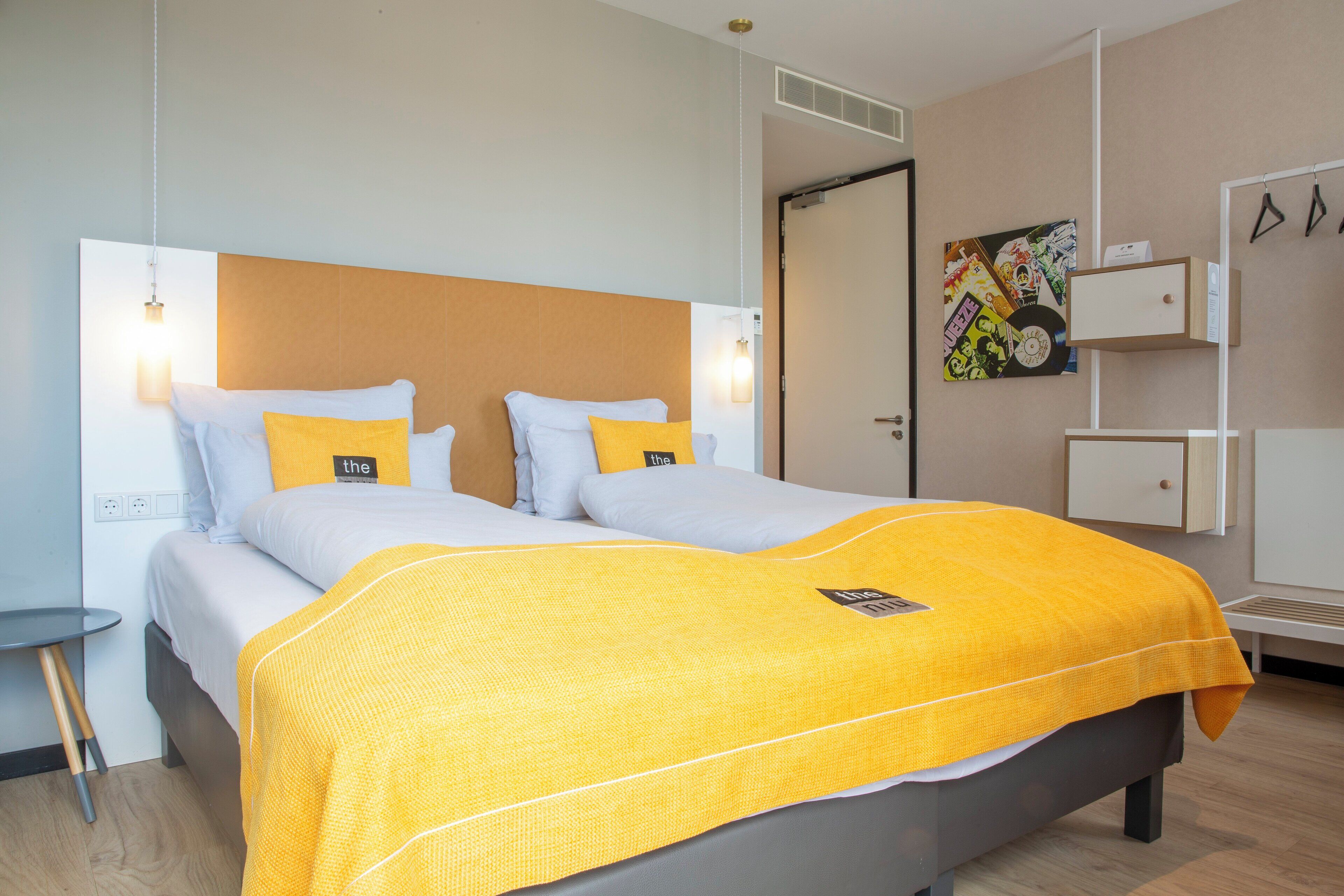 A double bed with a yellow blanket, white pillows, and a headboard.