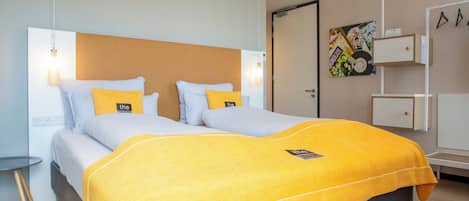 A double bed with a yellow blanket, white pillows, and a headboard.
