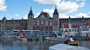 A historic building with multiple towers and a clock, situated by a canal with boats and a tram. - Holiday Inn - the niu, Dairy Haarlem by IHG (Haarlem)
