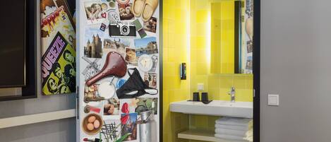 Un baño con pared de azulejos amarillos, un lavabo y un espejo.